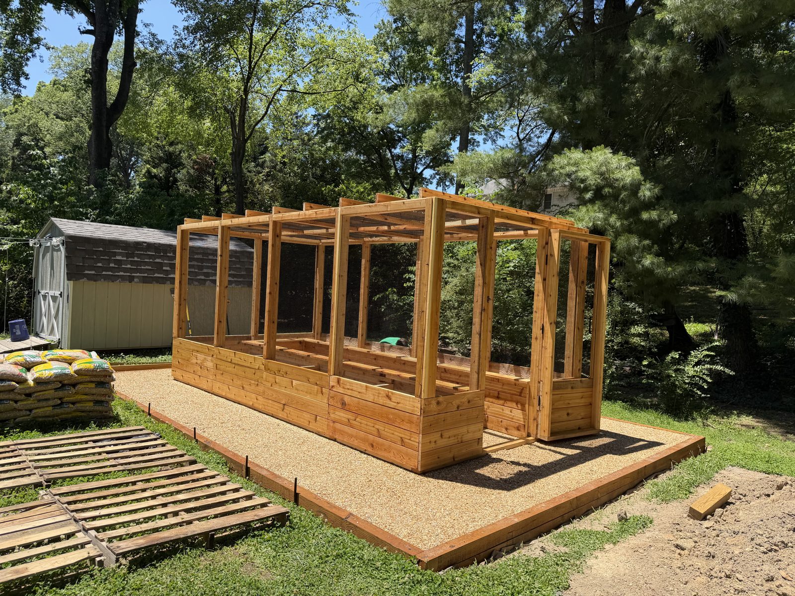 Large enclosed cedar garden system with double-door entry on a gravel base